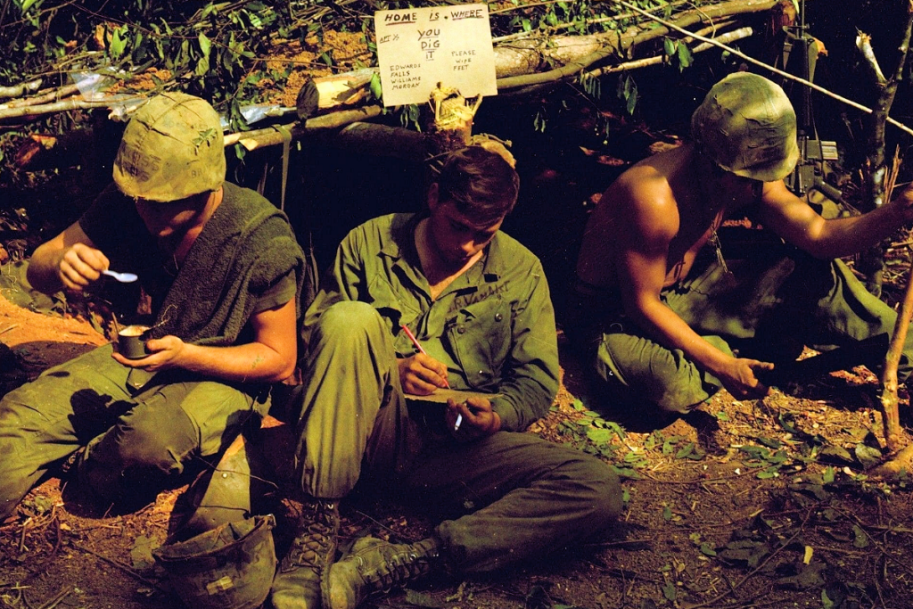 A group of three soldiers sitting in a trench.