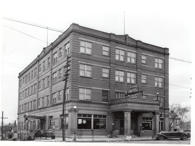 Image of a 4-story hotel Bottom is constructed of stone/masonry and top three floors are birck. there is a canopy over the front door supported by columns at the street side.