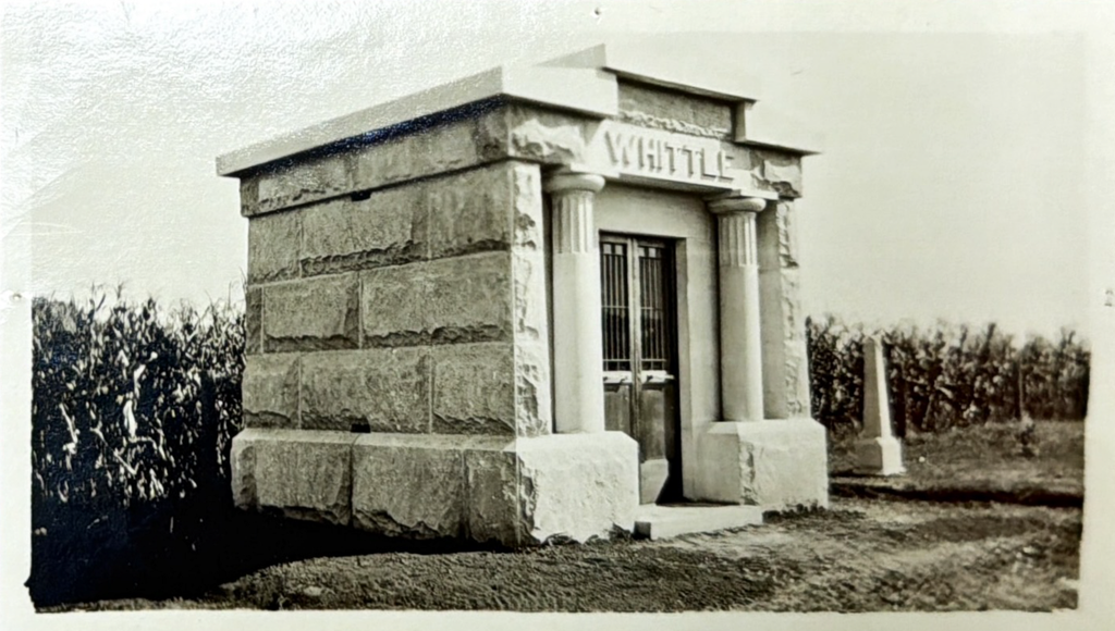 A black and white photo of Whittle Mausoleum soon after construction. A cornfield stands behind it. The ground around it appears to have been recently graded.